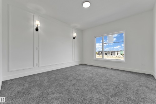 Wall paneling with sconce lighting, white walls, and gray carpet flooring - 261 Linden Loop, Leduc, AB 
