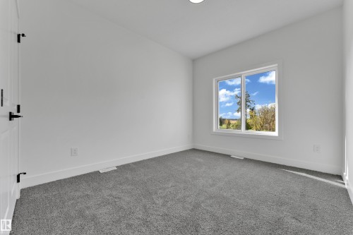 Neutral gray carpeting, white walls, and a large window with white trim - 261 Linden Loop, Leduc, AB 