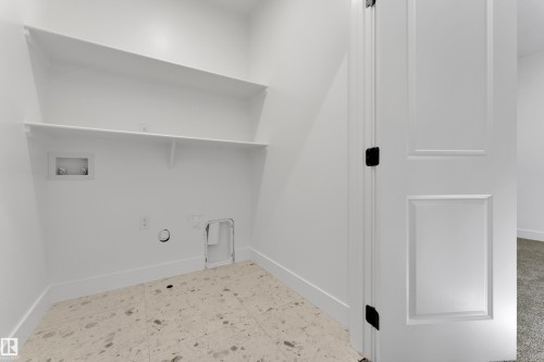 Laundry area featuring built-in shelving, durable flooring, and a paneled door with dark hardware - 261 Linden Loop, Leduc, AB 
