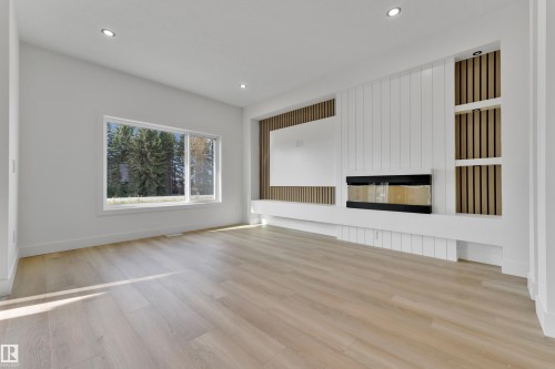 Recessed lighting, wood-finish flooring, a linear fireplace, built-in shelving, and a large window - 261 Linden Loop, Leduc, AB 