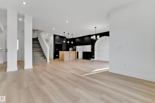 Light wood-finish flooring throughout, recessed lighting, and a staircase with carpeted treads - 261 Linden Loop, Leduc, AB 
