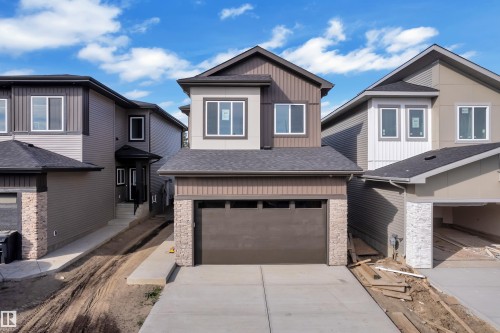 Two-story exterior featuring multi-toned siding, a dark shingle roof, white-framed windows, a single-car garage, and a concrete driveway - 247 Linden Loop, Leduc, AB 