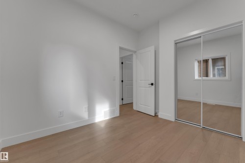 Wood-finish flooring, white walls, white doors, black door hardware, and mirrored closet doors - 247 Linden Loop, Leduc, AB 