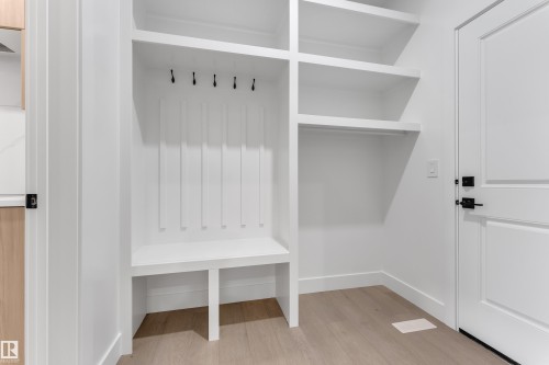 Built-in white storage unit featuring shelving, an integrated bench, and wall-mounted hooks - 247 Linden Loop, Leduc, AB 