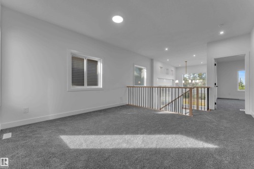 Carpeted landing with a white framed window, recessed lighting, and a wood and metal railing overlooking a lower level - 247 Linden Loop, Leduc, AB 