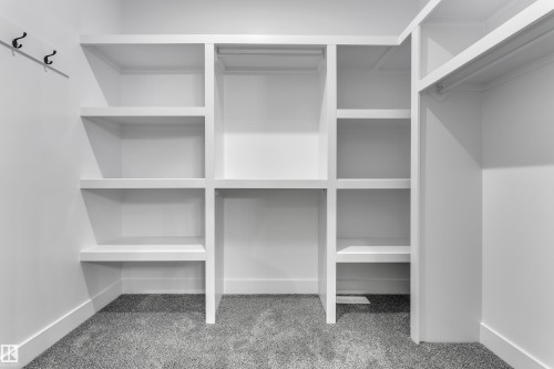 Built-in closet organization system featuring white shelving and hanging rods - 247 Linden Loop, Leduc, AB 