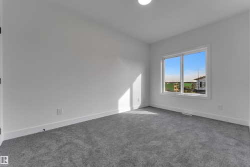 Bright interior space with white walls, gray carpeting, a single window, and a flush-mount ceiling light - 247 Linden Loop, Leduc, AB 