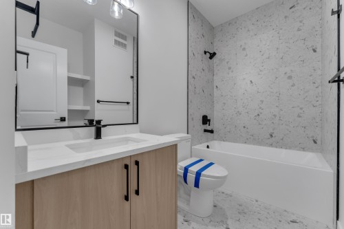 Bathroom vanity with wood-finish cabinetry, integrated sink, and matte black fixtures - 247 Linden Loop, Leduc, AB 
