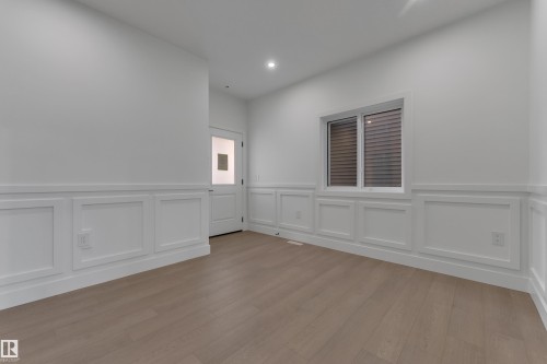 Light wood-finish flooring, white walls, wainscoting detail, recessed lighting, and a white interior door with a frosted glass pane - 247 Linden Loop, Leduc, AB 
