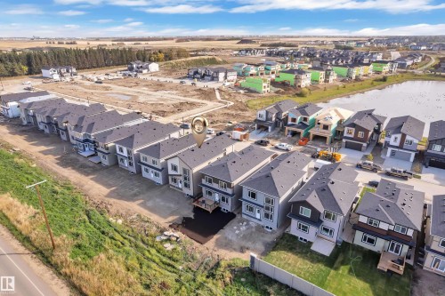 Modern residential development featuring multi-story homes with dark roofs and light-colored siding - 247 Linden Loop, Leduc, AB 