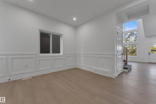 Wood-finish flooring throughout, white paneled wainscoting, recessed lighting, and a white window frame - 247 Linden Loop, Leduc, AB 
