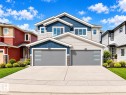 Two-story residence featuring a dual-tone facade, two modern garage doors with horizontal window inserts, a concrete driveway, and landscaped front yard with shrubs - 3718 67 Street, Beaumont, AB 