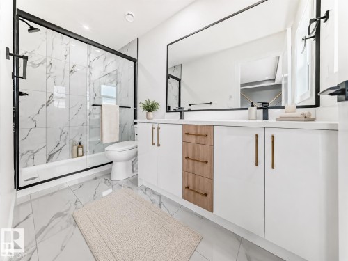 Dual-sink vanity with white cabinetry, wood-finish drawers, matte black fixtures, and a large mirror - 3718 67 Street, Beaumont, AB 
