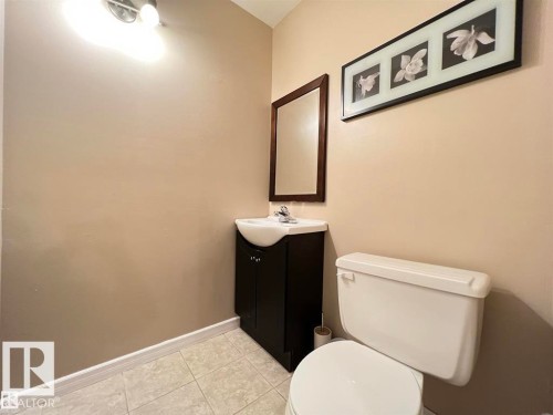Vanity with a white vessel sink, dark wood-finish cabinet, and a framed mirror - 144 Kaskitayo Court Nw, Edmonton, AB 