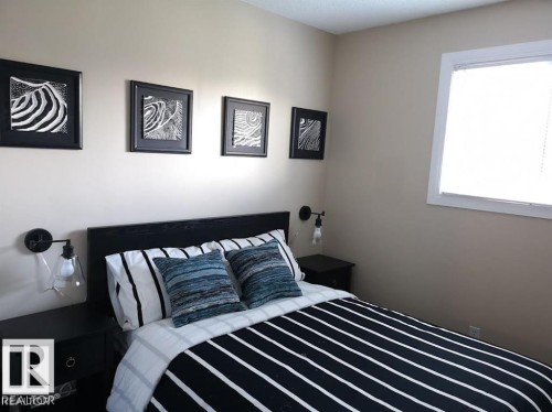 Built-in wall sconces with exposed bulbs, neutral wall color, and a window with white trim - 144 Kaskitayo Court Nw, Edmonton, AB 