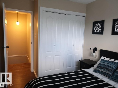 White bi-fold closet doors, wood-finish flooring, and a wall-mounted sconce - 144 Kaskitayo Court Nw, Edmonton, AB 