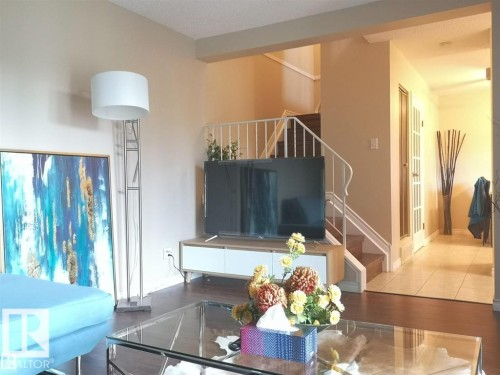Hardwood-finish flooring, staircase with white railing, and a hallway featuring a French door - 144 Kaskitayo Court Nw, Edmonton, AB 
