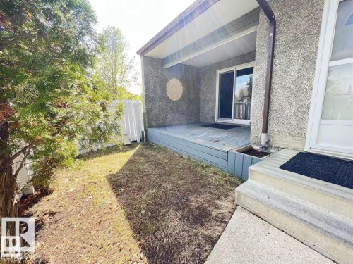 Covered deck with a sliding glass door, concrete steps, and a white fence - 144 Kaskitayo Court Nw, Edmonton, AB 