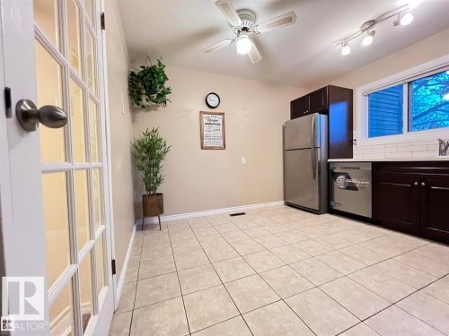 Tile flooring, dark wood-finish cabinetry, white subway tile backsplash, stainless steel appliances, and a ceiling fan with integrated lighting - 144 Kaskitayo Court Nw, Edmonton, AB 