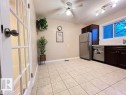 Tile flooring, dark wood-finish cabinetry, white subway tile backsplash, stainless steel appliances, and a ceiling fan with integrated lighting - 144 Kaskitayo Court Nw, Edmonton, AB 