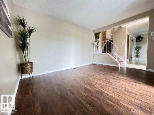 Wood-finish flooring, neutral wall tones, white trim, staircase with white railing, and a tiled entry - 144 Kaskitayo Court Nw, Edmonton, AB 