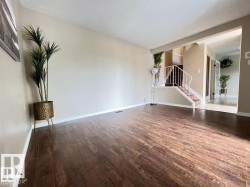 Wood-finish flooring, neutral wall tones, white trim, staircase with white railing, and a tiled entry - 