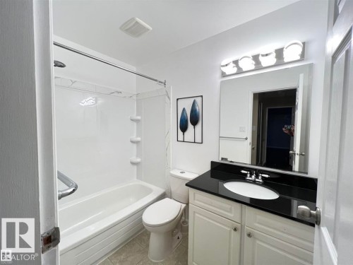White vanity with a black countertop, integrated sink, and chrome faucet - 144 Kaskitayo Court Nw, Edmonton, AB 