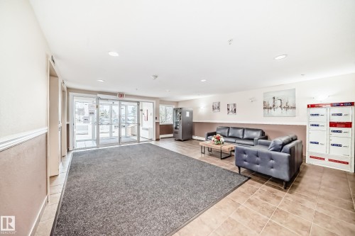 Spacious common area featuring recessed lighting, tile flooring, and automatic glass entry doors - #302 4309 33 St, Stony Plain, AB 