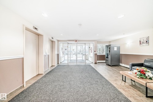 Lobby featuring two elevators, glazed double entrance doors, tiled flooring, and recessed ceiling lighting - #302 4309 33 St, Stony Plain, AB 