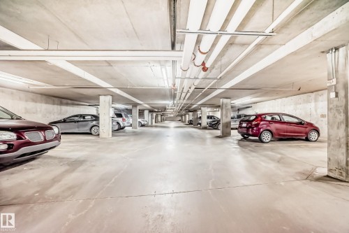 Underground parking garage featuring concrete pillars, overhead lighting, and exposed utility pipes - #302 4309 33 St, Stony Plain, AB 