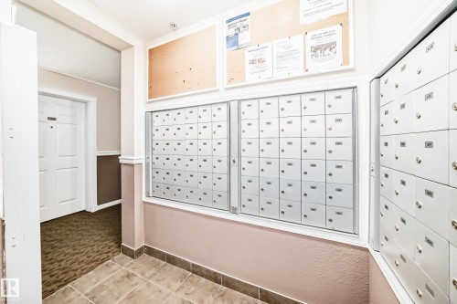 Hallway featuring individual mailboxes, a bulletin board, and tile flooring - #302 4309 33 St, Stony Plain, AB 