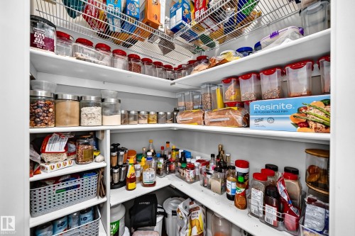 Built-in pantry shelving featuring white wood shelves and wire racks - 1673 Cunningham Way Sw, Edmonton, AB 