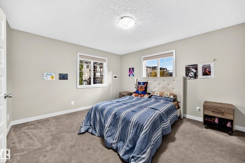 Neutral wall color, two windows with white trim, wall-to-wall carpeting, white ceiling, and a flush-mount ceiling light fixture - 1673 Cunningham Way Sw, Edmonton, AB 