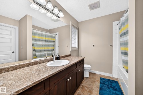 Bathroom featuring a single basin vanity, dark wood-finish cabinetry, and a full-width mirror - 1673 Cunningham Way Sw, Edmonton, AB 