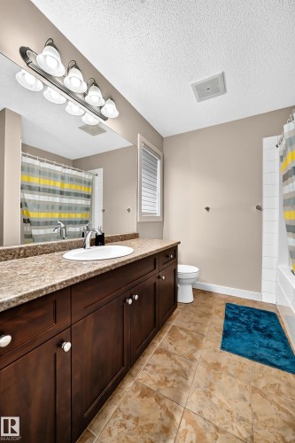 Spacious vanity with a composite countertop, an undermount sink, and dark wood cabinetry - 1673 Cunningham Way Sw, Edmonton, AB 