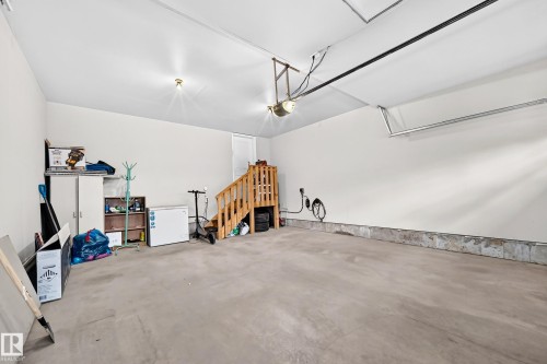 Concrete flooring with painted walls, overhead lighting, and an exposed wood staircase - 1673 Cunningham Way Sw, Edmonton, AB 
