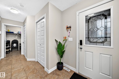 Entryway featuring a decorative glass panel door, neutral wall paint, tile flooring, and integrated lighting - 1673 Cunningham Way Sw, Edmonton, AB 