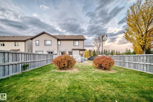 Expansive backyard with a manicured lawn, established shrubs, and a wood privacy fence - 1673 Cunningham Way Sw, Edmonton, AB 