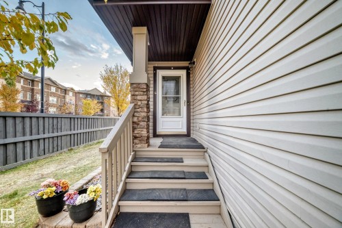 Exterior entry featuring white siding and a wood privacy fence - 1673 Cunningham Way Sw, Edmonton, AB 