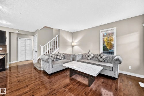 Hardwood flooring, painted interior walls, white trim, white staircase with wood handrail, and a window with white casing - 1673 Cunningham Way Sw, Edmonton, AB 