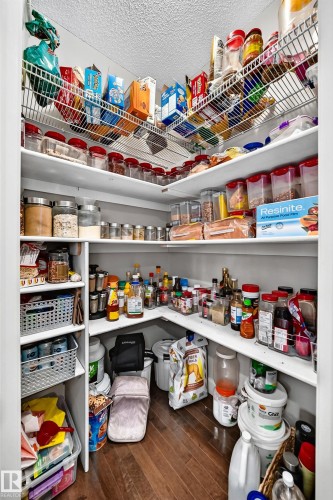 Walk-in pantry with wood-finish flooring, white shelving, and wire shelving - 1673 Cunningham Way Sw, Edmonton, AB 