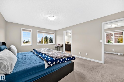 Soft gray wall paint, textured ceiling, two large windows, white trim, and a semi-flush mount light fixture - 1673 Cunningham Way Sw, Edmonton, AB 