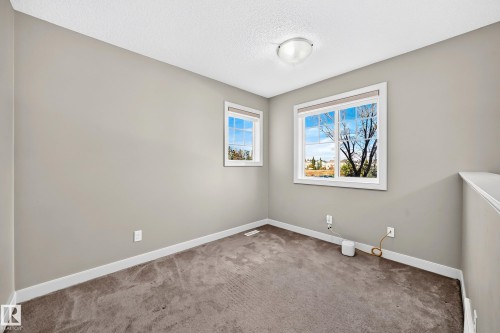 Carpeted flooring, two windows with white trim, neutral wall paint, and a semi-flush mount ceiling light fixture - 1673 Cunningham Way Sw, Edmonton, AB 