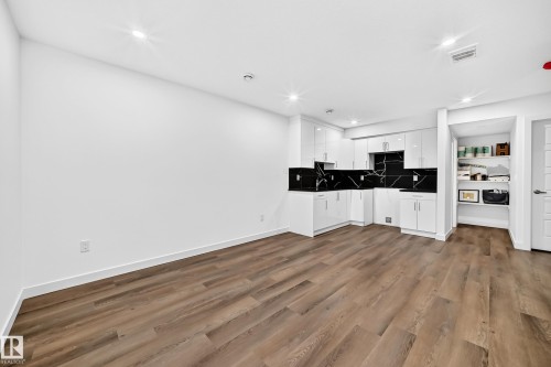 Wood-finish flooring, white walls, recessed lighting, white cabinetry, and black patterned backsplash - 1673 Cunningham Way Sw, Edmonton, AB 