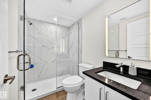 Glass-enclosed shower with white marble-style tile, a built-in shower niche, and a chrome shower head - 1673 Cunningham Way Sw, Edmonton, AB 