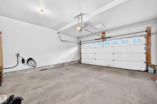 Attached garage with a concrete floor, overhead lighting, and an electric vehicle charging station - 1673 Cunningham Way Sw, Edmonton, AB 