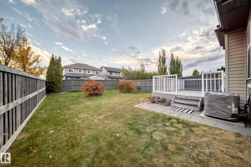 Private backyard featuring a wood privacy fence, a raised deck with white railings, and a paver patio - 1673 Cunningham Way Sw, Edmonton, AB 