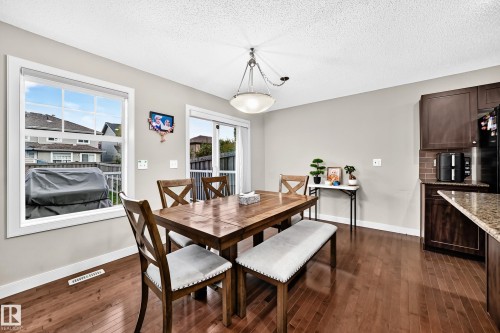 Hardwood flooring, neutral wall paint, modern ceiling fixture, sliding patio door, and kitchen cabinetry - 1673 Cunningham Way Sw, Edmonton, AB 