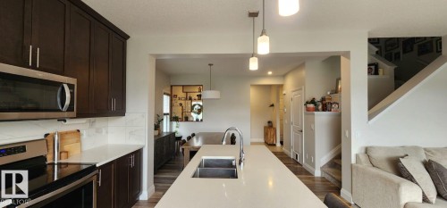 Modern kitchen featuring dark wood-finish cabinetry, stainless steel appliances, and a double basin sink - 3779 Cherry Loop Sw, Edmonton, AB 