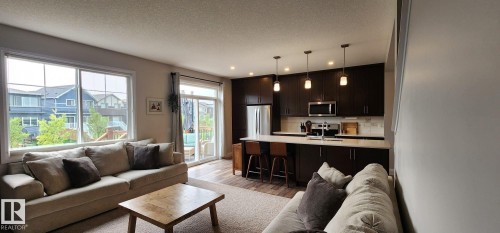 Open-concept living space featuring wood-finish flooring, recessed lighting, and large windows - 3779 Cherry Loop Sw, Edmonton, AB 